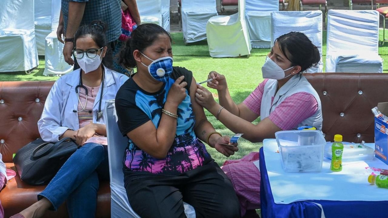 A health worker inoculates a woman with a dose of the Covishield vaccine against the Covid-19 coronavirus at a temporary vaccination centre in New Delhi. Credit: AFP Photo