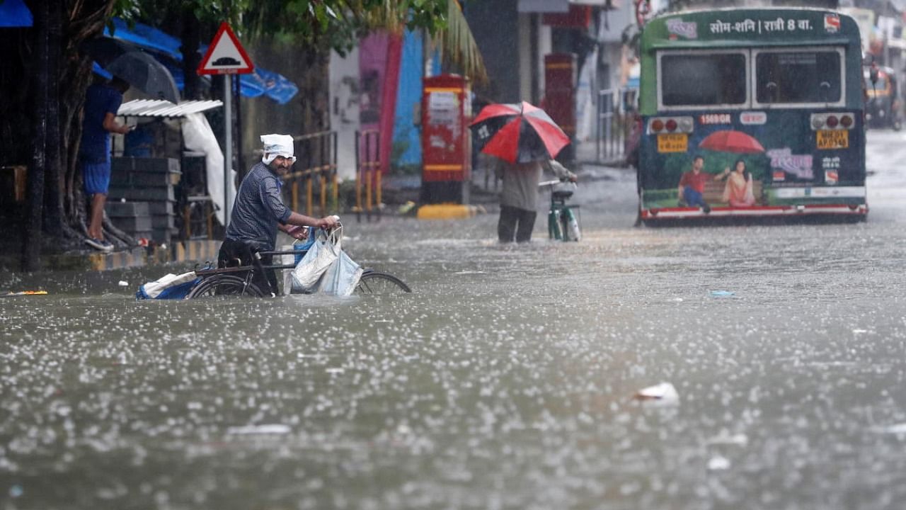 People wade through a waterlogged road after heavy rainfall in Mumbai. Credit: Reuters Photo
