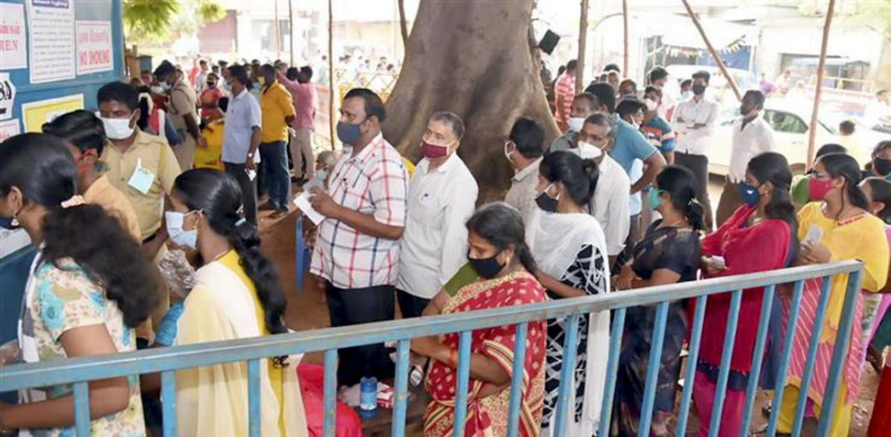 Voters stand in a queue to cast their votes, at a polling booth, during the Puducherry Assembly Election, in Pudupet, Puducherry. Credit: PTI Photo