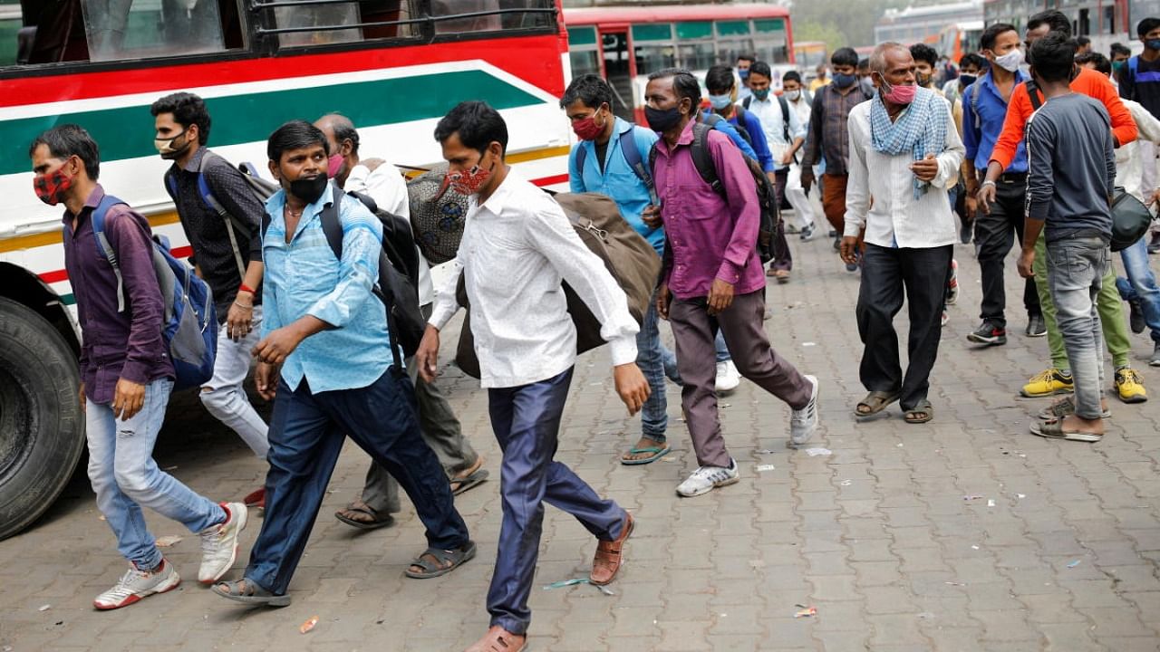 Migrant workers run after a moving bus to board, as they return to their villages, after Delhi government ordered a six-day lockdown. Credit: Reuters Photo