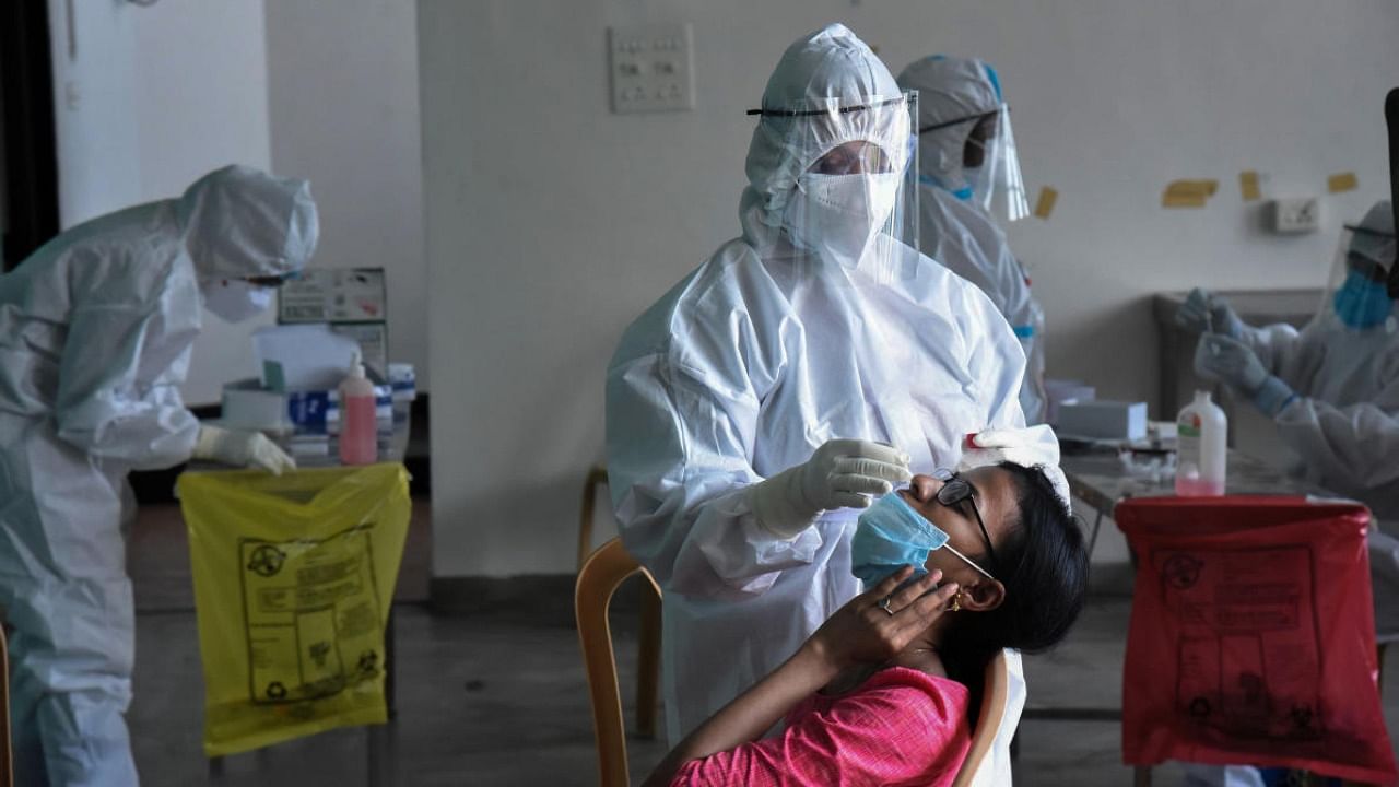 A medic, in PPE suit, collects nasal swab for Covid-19 test, amid the rise in Covid-19 cases across the country, Kochi. Credit: PTI Photo