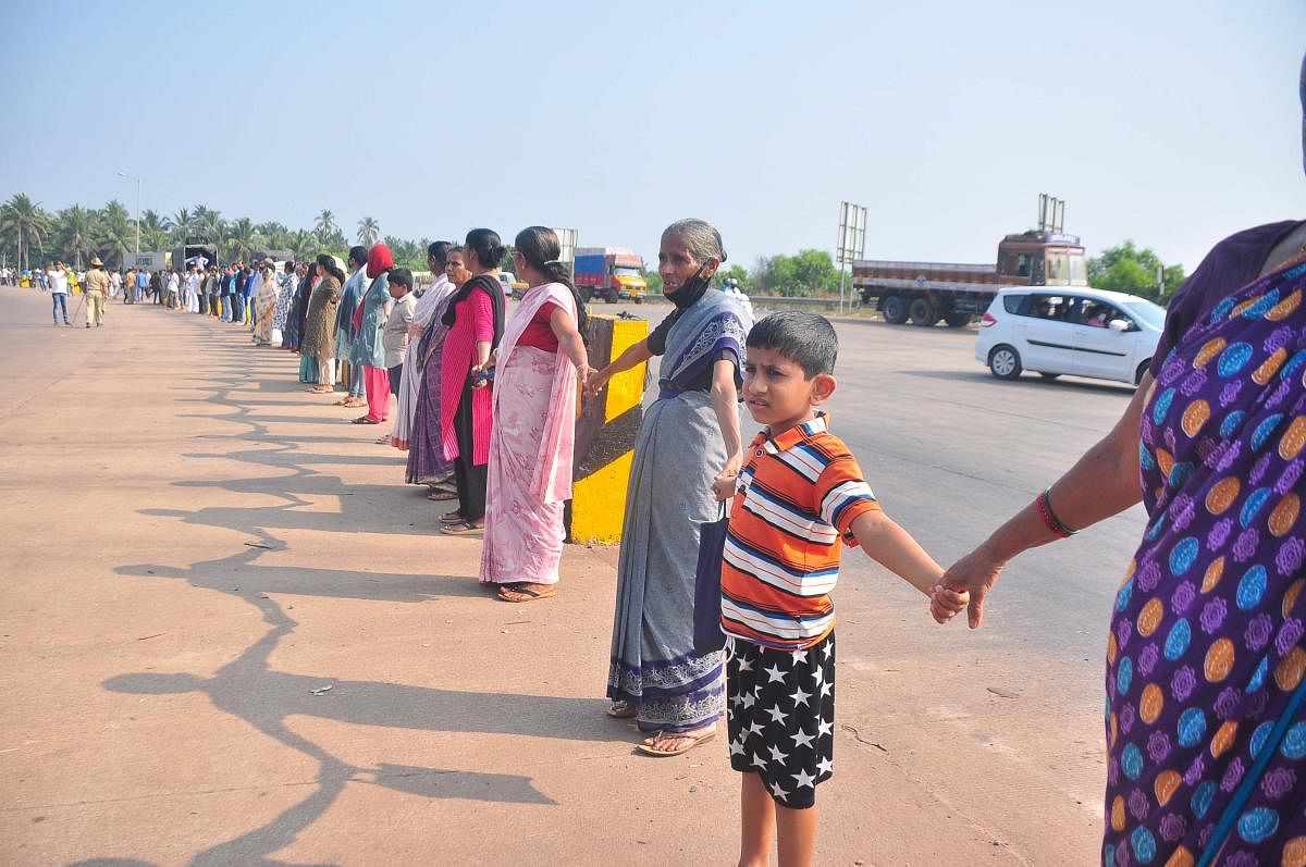 Residents and regular travellers from Kerala form a human chain demanding that buses should end the trip at Talapady bus stand on Wednesday.