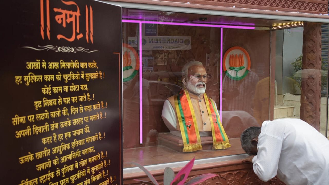A supporter of Prime Minister Narendra Modi pays him tribute at his newly built statue inside a temple by Namo Foundation, at Aundh in Pune, Tuesday, August 17, 2021. Credit: PTI Photo