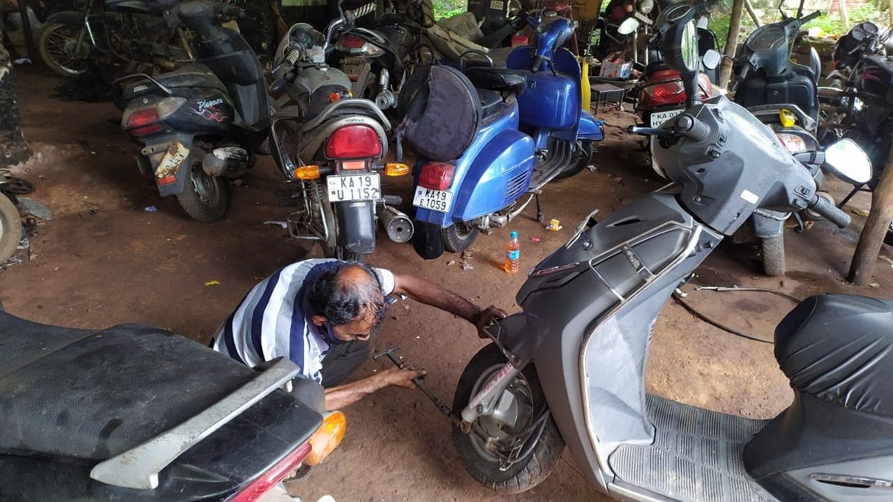 A mechanic fixes a two-wheeler in a garage in Mangaluru. DH Photo/Govindraj Javali