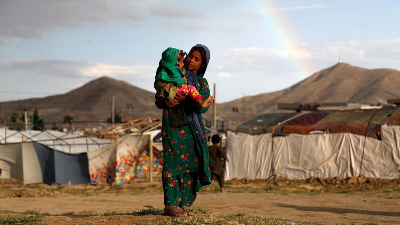  An internally displaced Afghan girl carries a child near their shelter at a refugee camp on the outskirts of Kabul, Afghanistan June 20, 2019. Credit: Reuters Photo