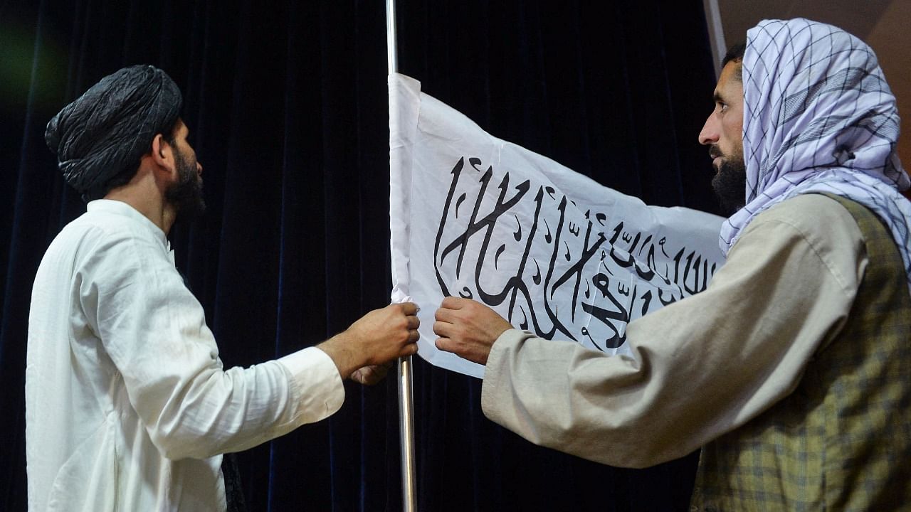 Men adjust the Taliban flag before the arrival of Taliban spokesperson Zabihullah Mujahid (unseen) to address the first press conference in Kabul. Credit: AFP Photo