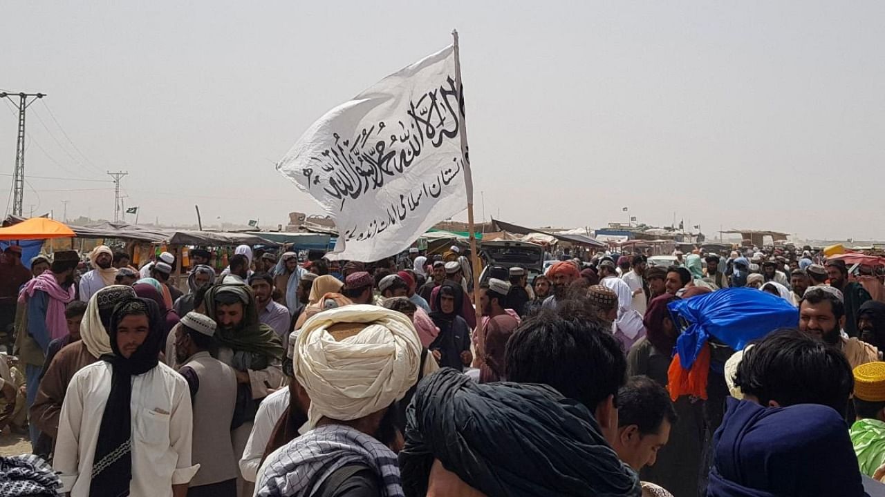 People gather around a Taliban flag as they wait for relatives released from jail in Afghanistan following an 'amnesty' by the Taliban. Credit: AFP Photo