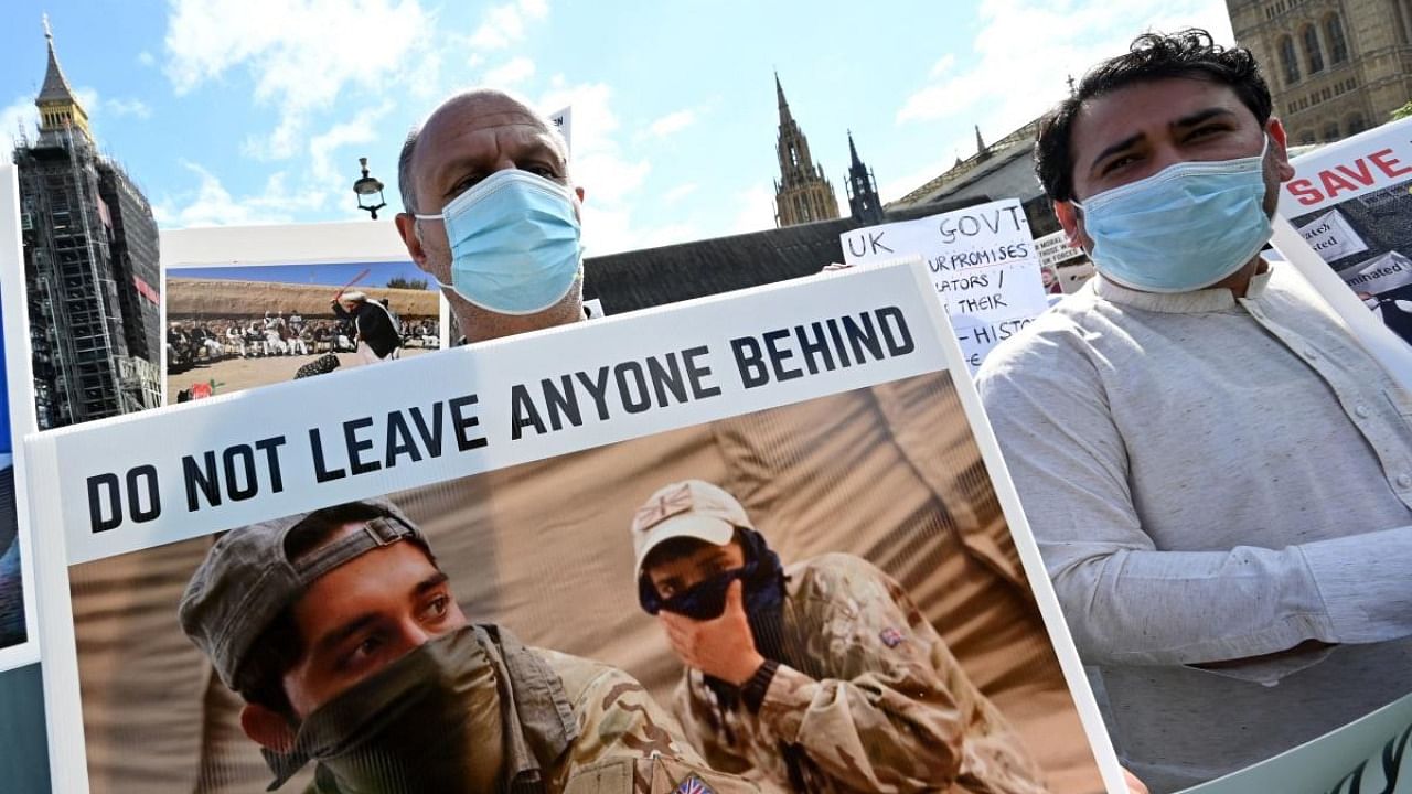 Demonstrators, including former interpreters for the British Army in Afghanistan, hold placards as they protest opposite the Houses of Parliament in London. Credit: AFP Photo