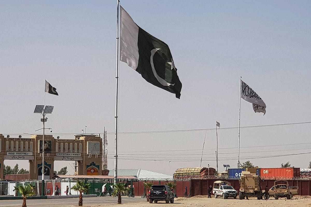 Pakistani flags (C) and Taliban flag (R) flutter on their respective border sides as seen from the Pakistan-Afghanistan border crossing point in Chaman on August 18, 2021. AFP