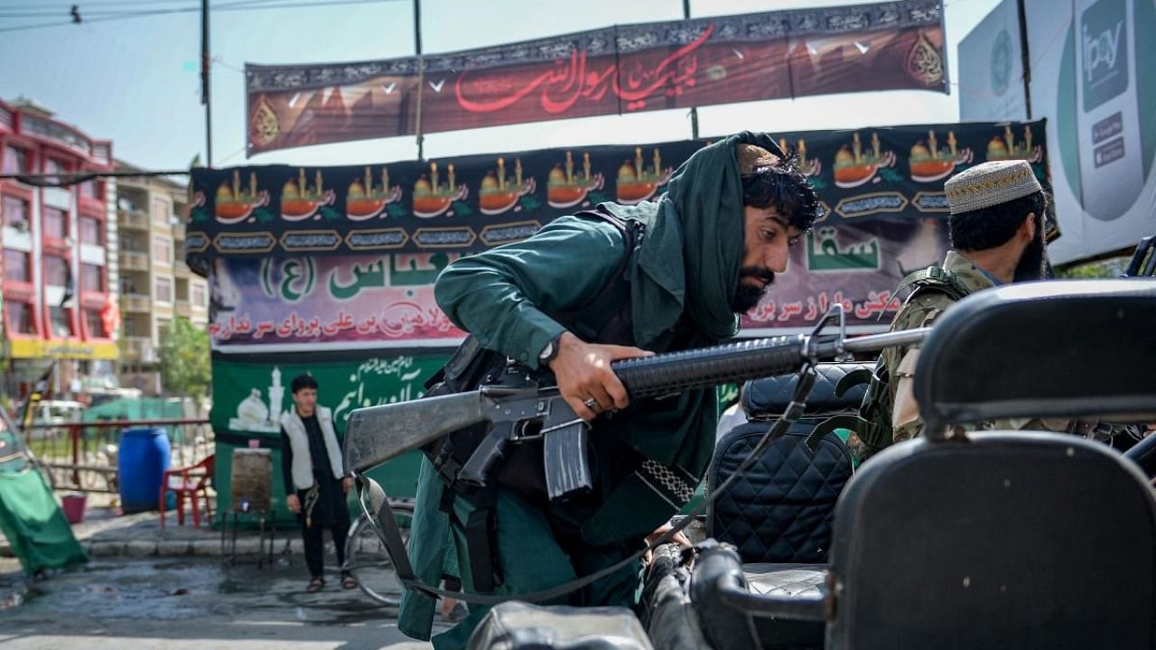 A Taliban fighter clibms up on a vehicle along a makeshift tent where the Shiite Muslims distribute sherbet to people during the Ashura procession which is held to mark the death of Imam Hussein, the grandson of Prophet Mohammad, along a road in Kabul on August 19, 2021, amid the Taliban's military takeover of Afghanistan. Credit: AFP Photo