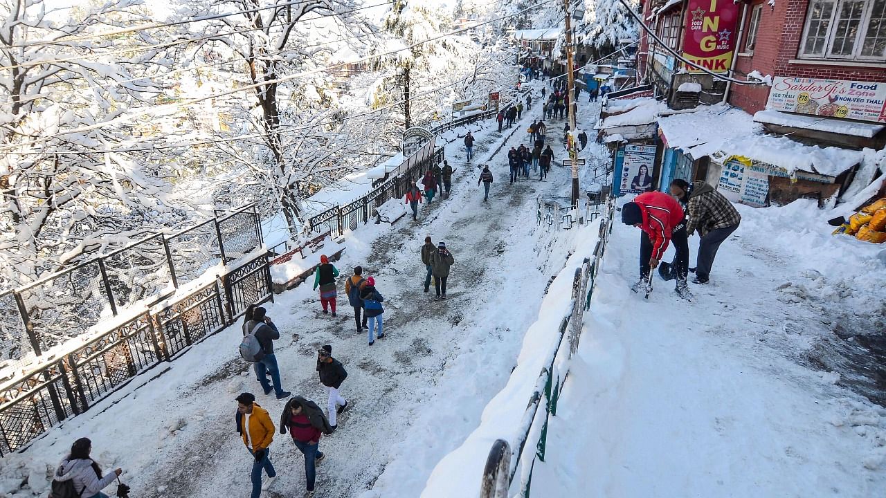  People walk on a snow covered road after heavy snowfall in Shimla. Credit: PTI File Photo
