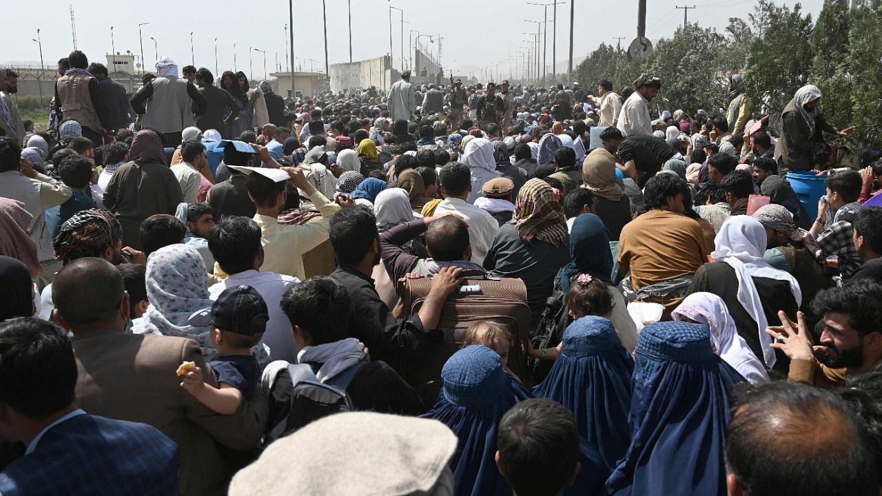 Afghans gather on a roadside near the military part of the airport in Kabul hoping to flee from the country after the Taliban's military takeover. Credit: AFP File Photo