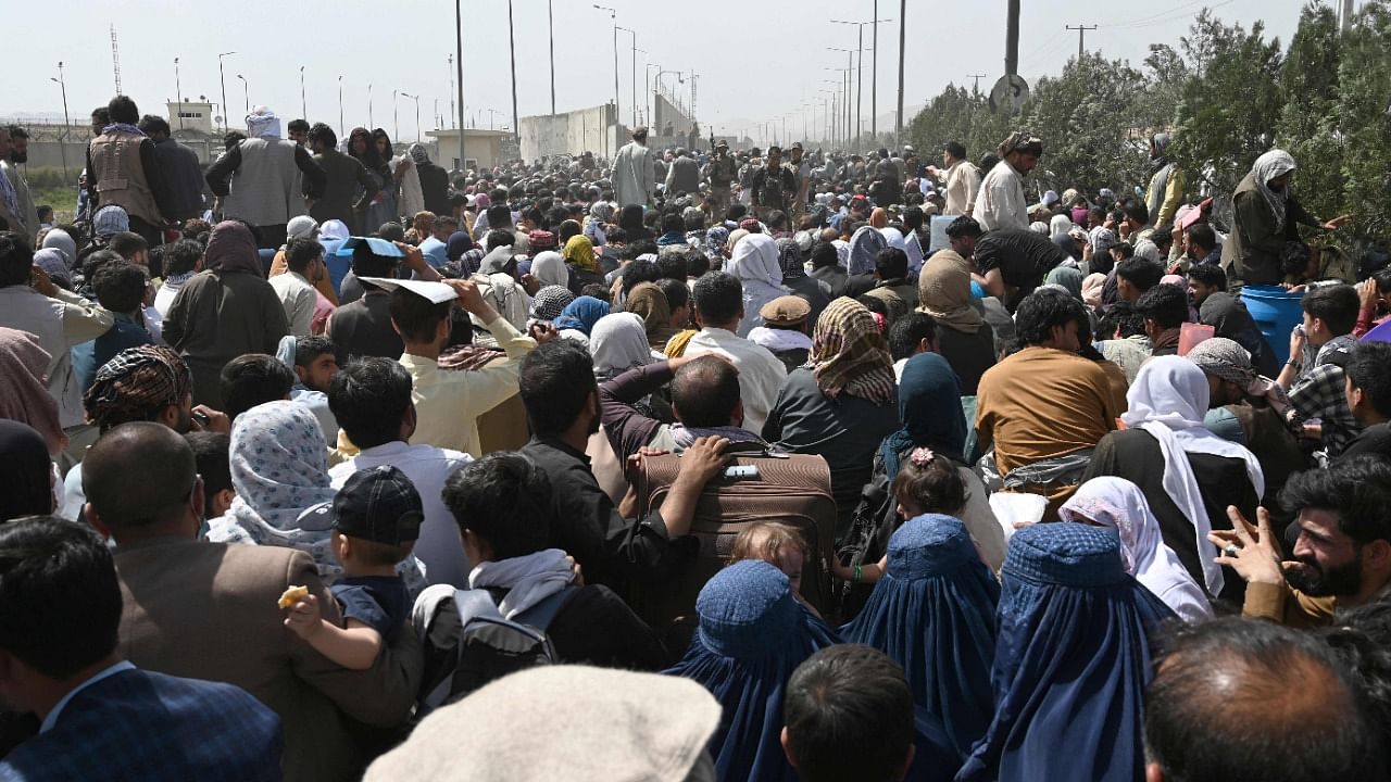 Afghans gather on a roadside near the military part of the airport in Kabul on August 20, 2021, hoping to flee from the country after the Taliban's military takeover of Afghanistan. Credit: AFP Photo