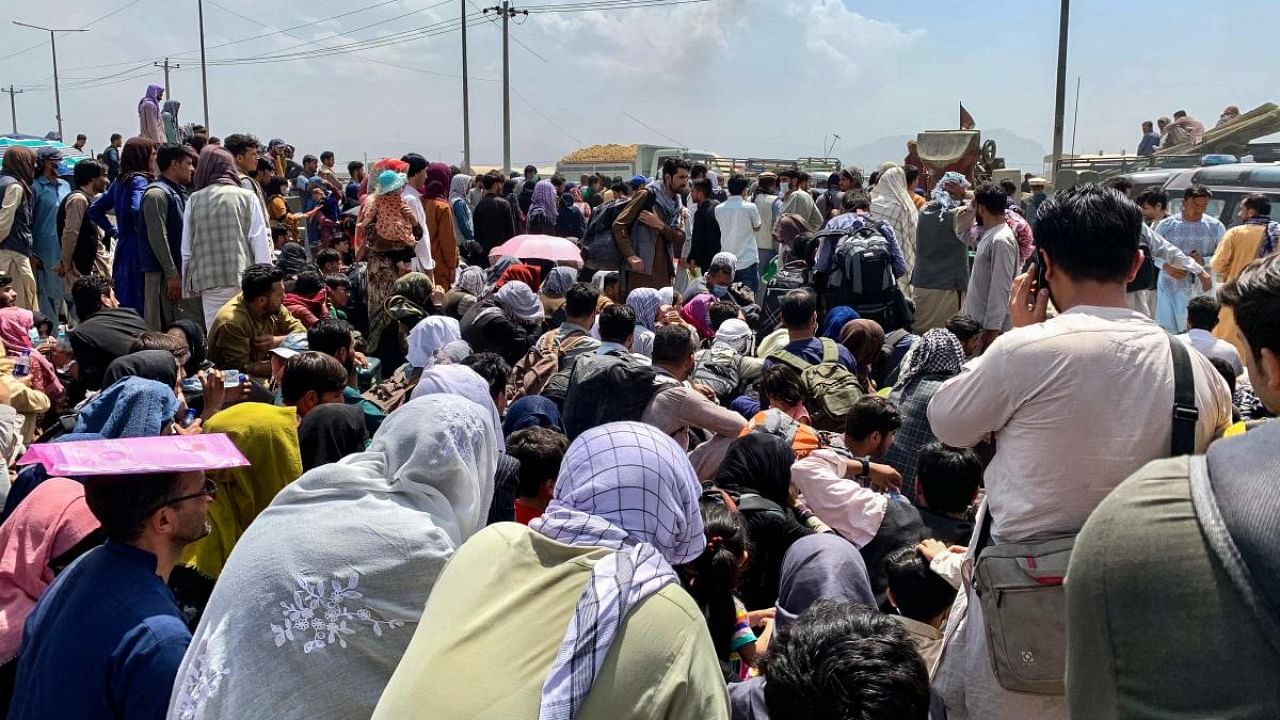 Afghan people gather along a road as they wait to board a US military aircraft to leave the country, at a military airport in Kabul on August 20, 2021 days after Taliban's military takeover of Afghanistan. Credit: AFP Photo