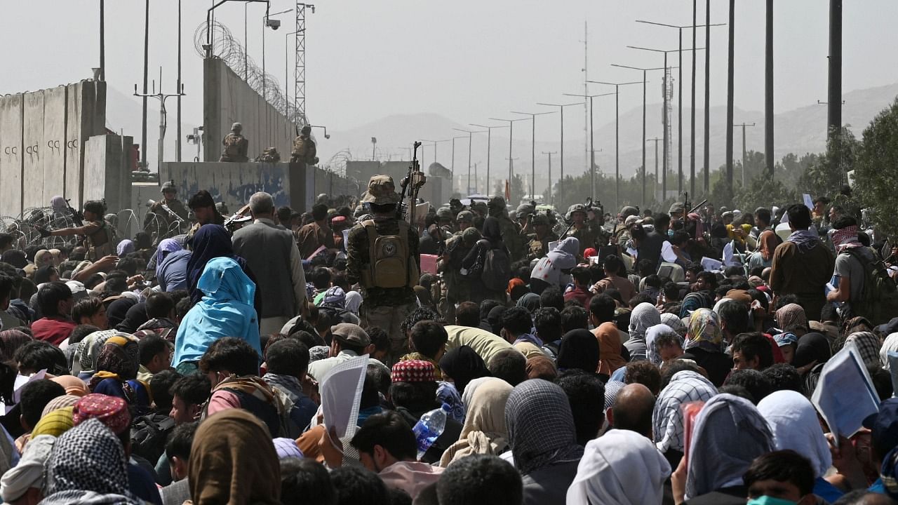 Afghans gather on a roadside near the military part of the airport in Kabul. Credit: AFP File Photo