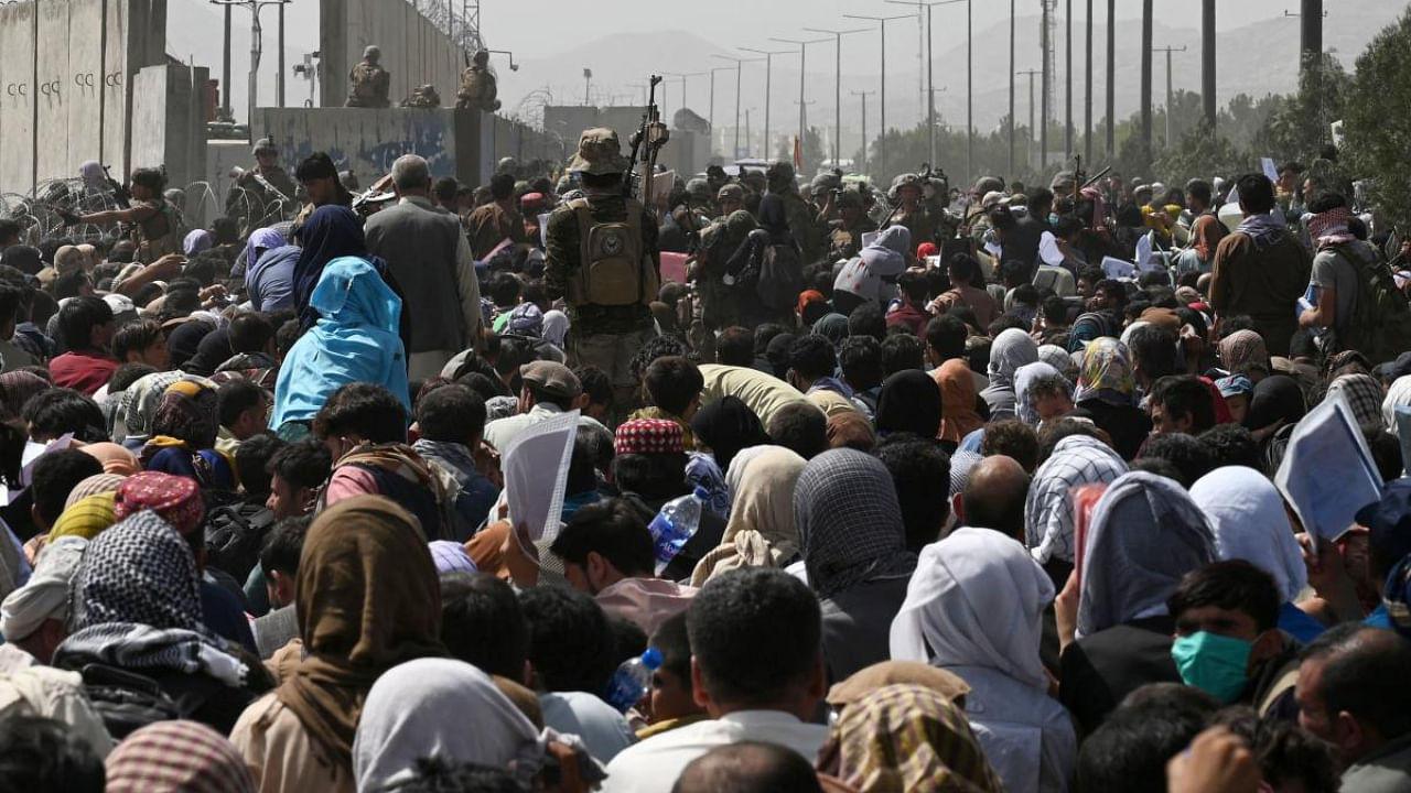 Afghans gather on a roadside near the military part of the airport in Kabul on August 20, 2021, hoping to flee from the country after the Taliban's military takeover of Afghanistan. Credit: AFP Photo