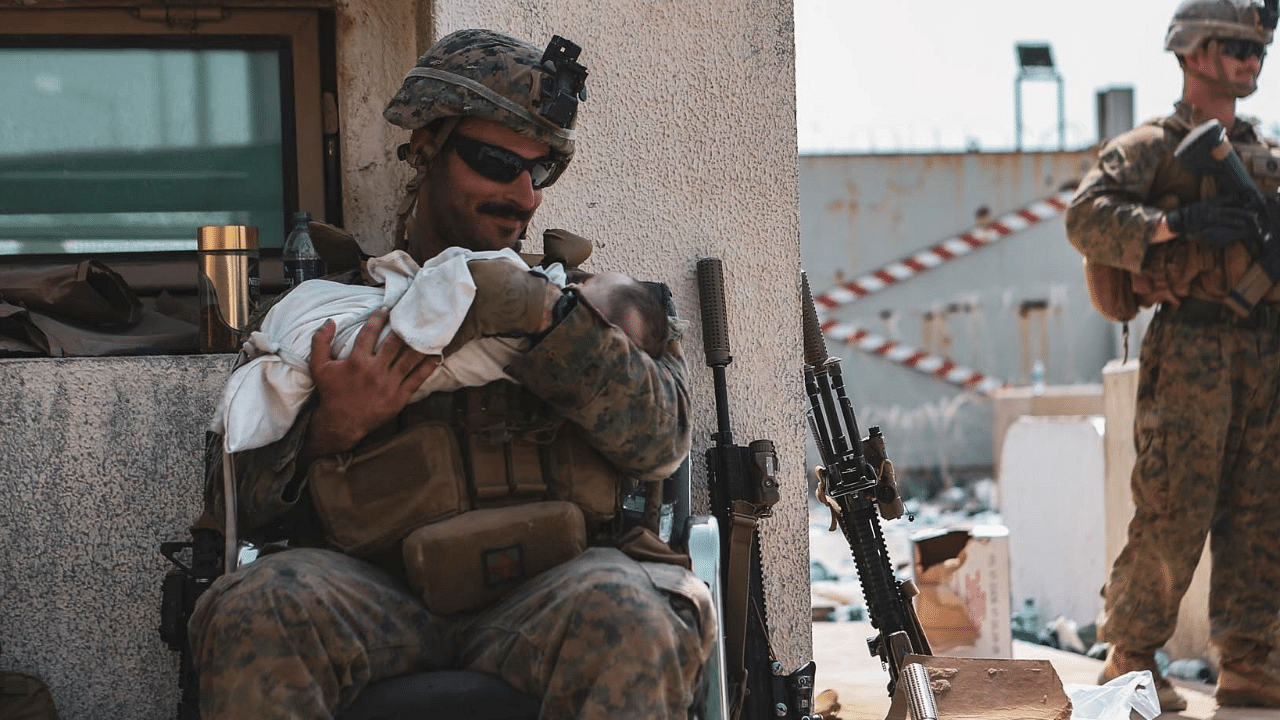 A US Marine assigned to the 24th Marine Expeditionary Unit (MEU) holds a baby during an evacuation at Hamid Karzai International Airport, Kabul. Credit: Reuters Photo
