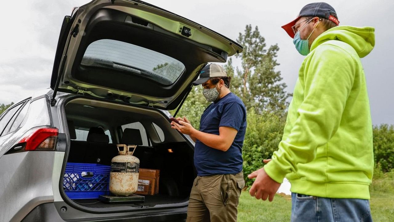 Chad Dorger (L), Senior Environmental Program Associate at Tradewater Refrigerant Solutions, picks up empty refrigerant tanks from Rick Karas (R). Credit: AFP Photo