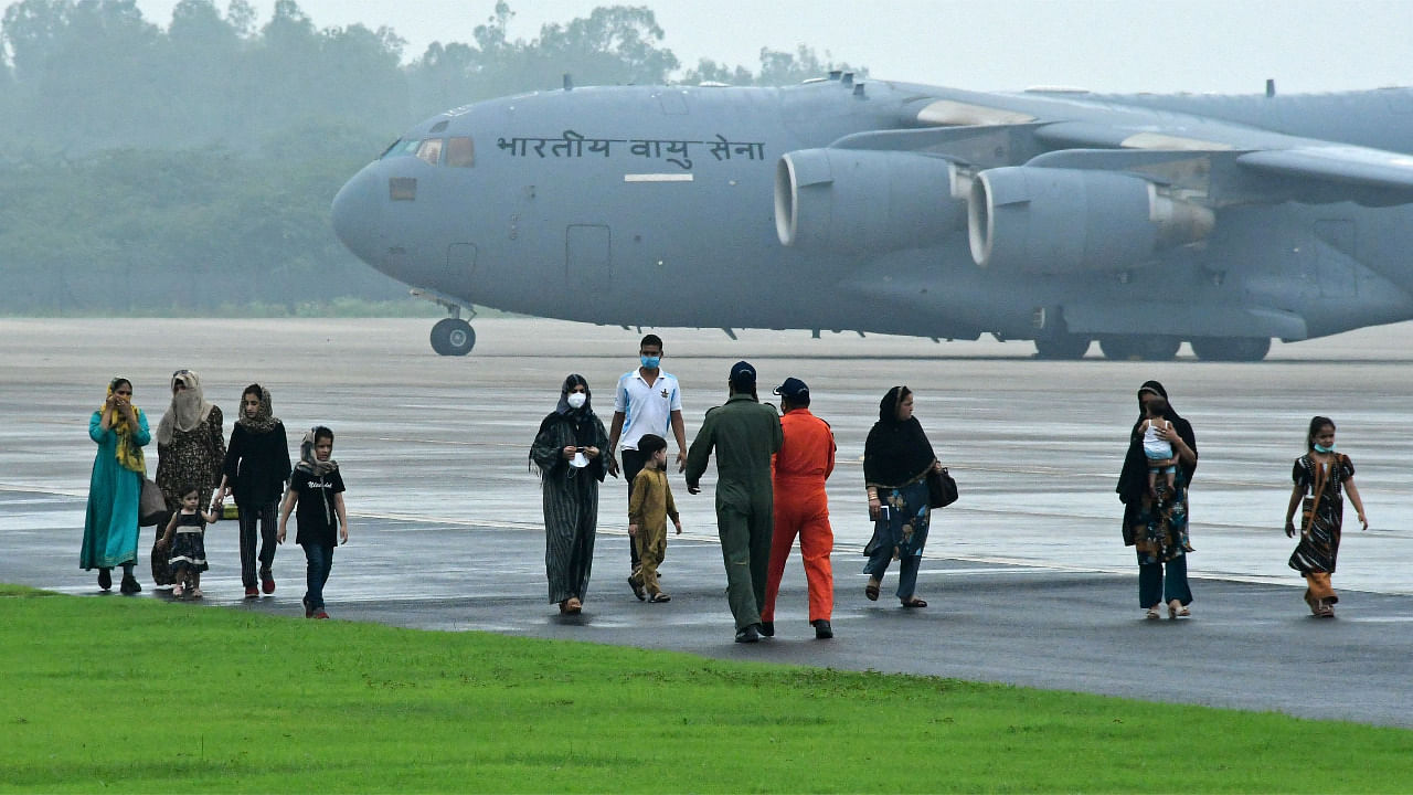 Evacuees from Afghanistan walk through the tarmac after disembarking from an Indian Air Force (IAF) aircraft at Hindon Air Force Station in Ghaziabad. Credit: AFP Photo