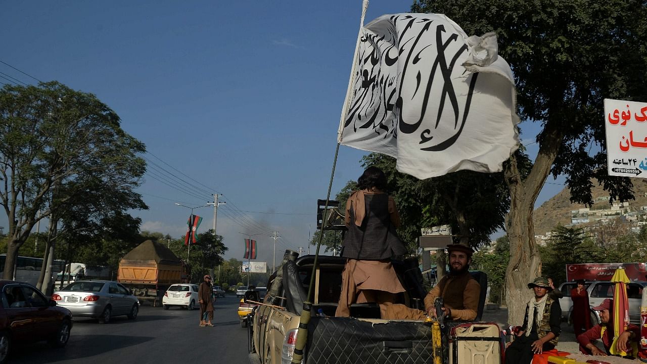 Taliban fighters travel on a vehicle mounted with the Taliban flag in the Karte Mamorin area of Kabul. Credit: AFP Photo