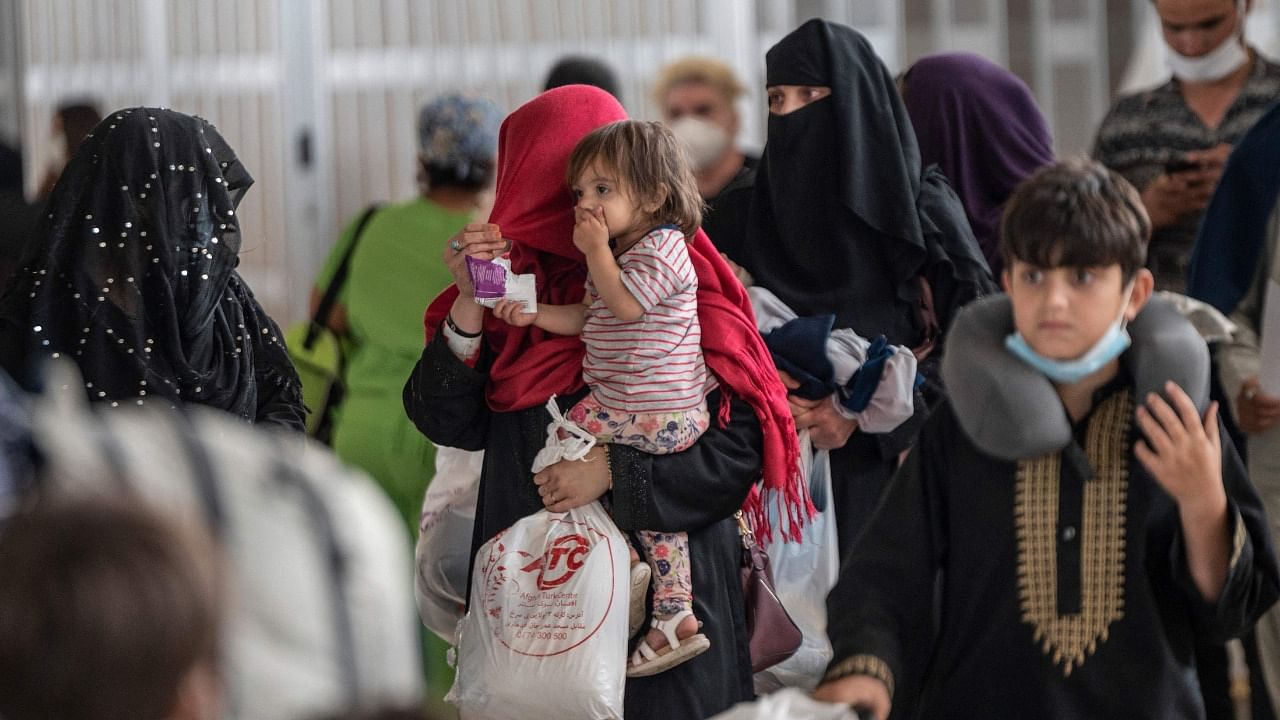 Refugees from Afghanistan are escorted to a waiting bus after arriving and being processed at Dulles International Airport in Dulles, Virginia. Credit: AFP Photo