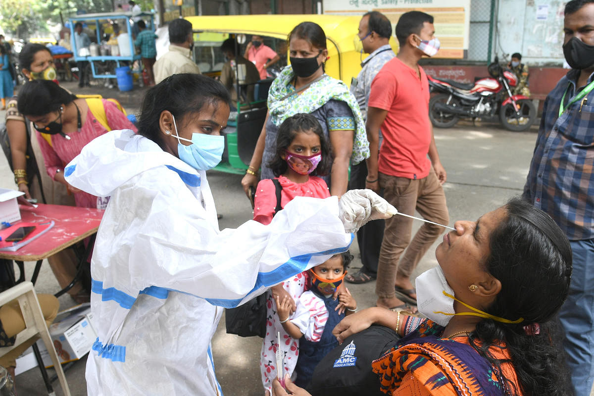 A health worker collects swabs from passengers for Covid test at Krantiveera Sangolli Rayanna Railway Station in Bengaluru on Sunday. Credit: DH Photo/S K Dinesh