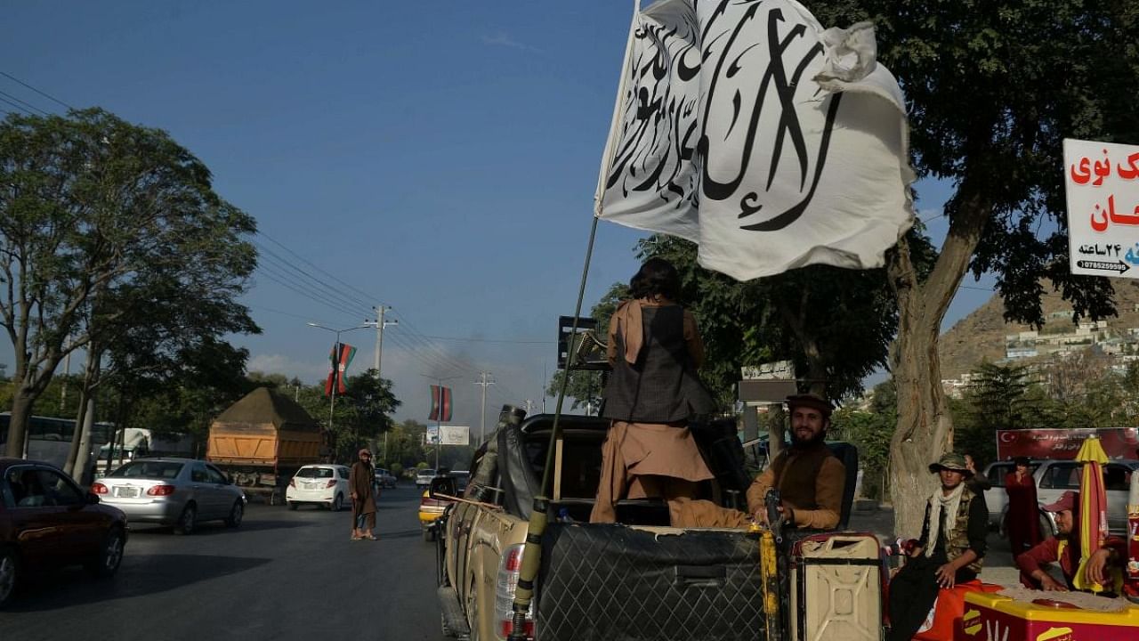 Taliban fighters travel on a vehicle mounted with the Taliban flag in the Karte Mamorin area of Kabul. Credit: AFP Photo