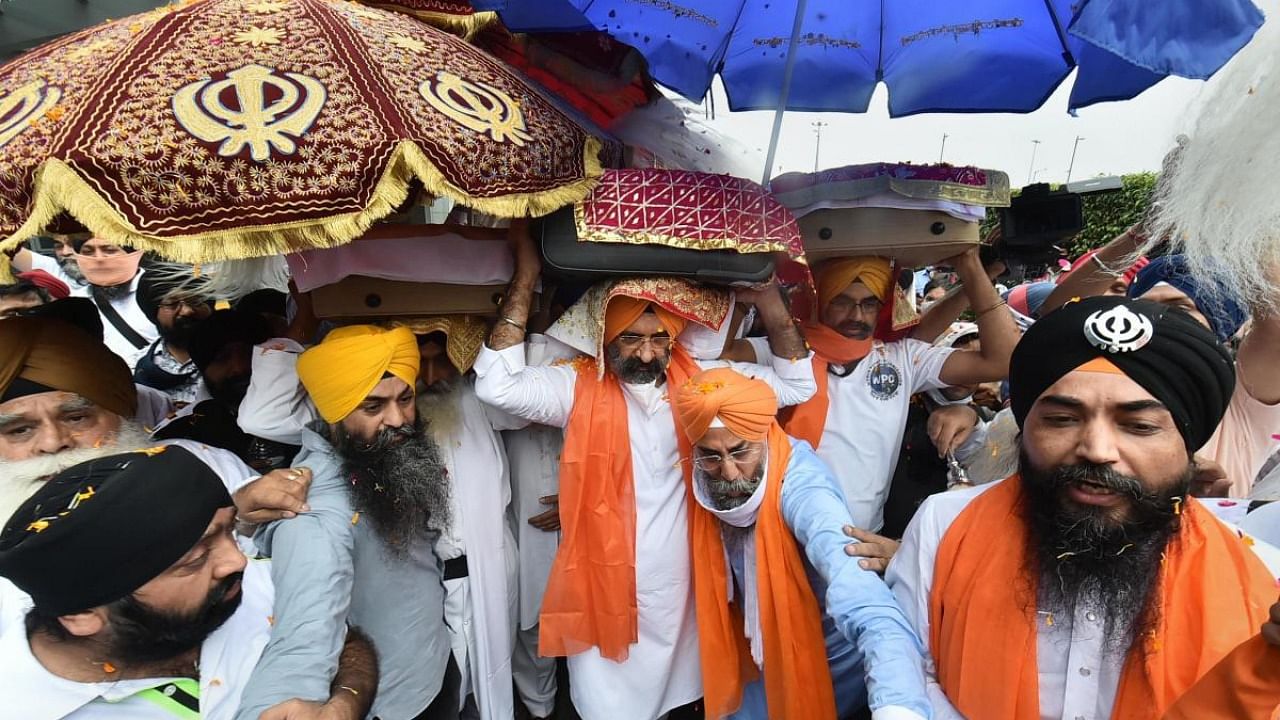 Sikh Community receive swaroop of Shri Guru Granth Sahib Maharaj brought from Afghanistan, along with Afghani Sikh members at IGI Terminal 3 Airport in New Delhi, Tuesday, Aug. 24, 2021. Credit: PTI Photo