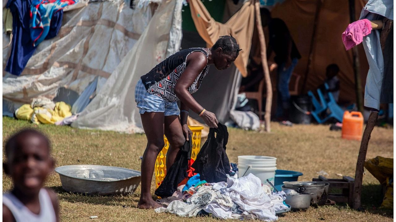 A woman washes clothes at a camp for people who lost their home during the August 14 earthquake in Les Cayes. Credit: AFP Photo