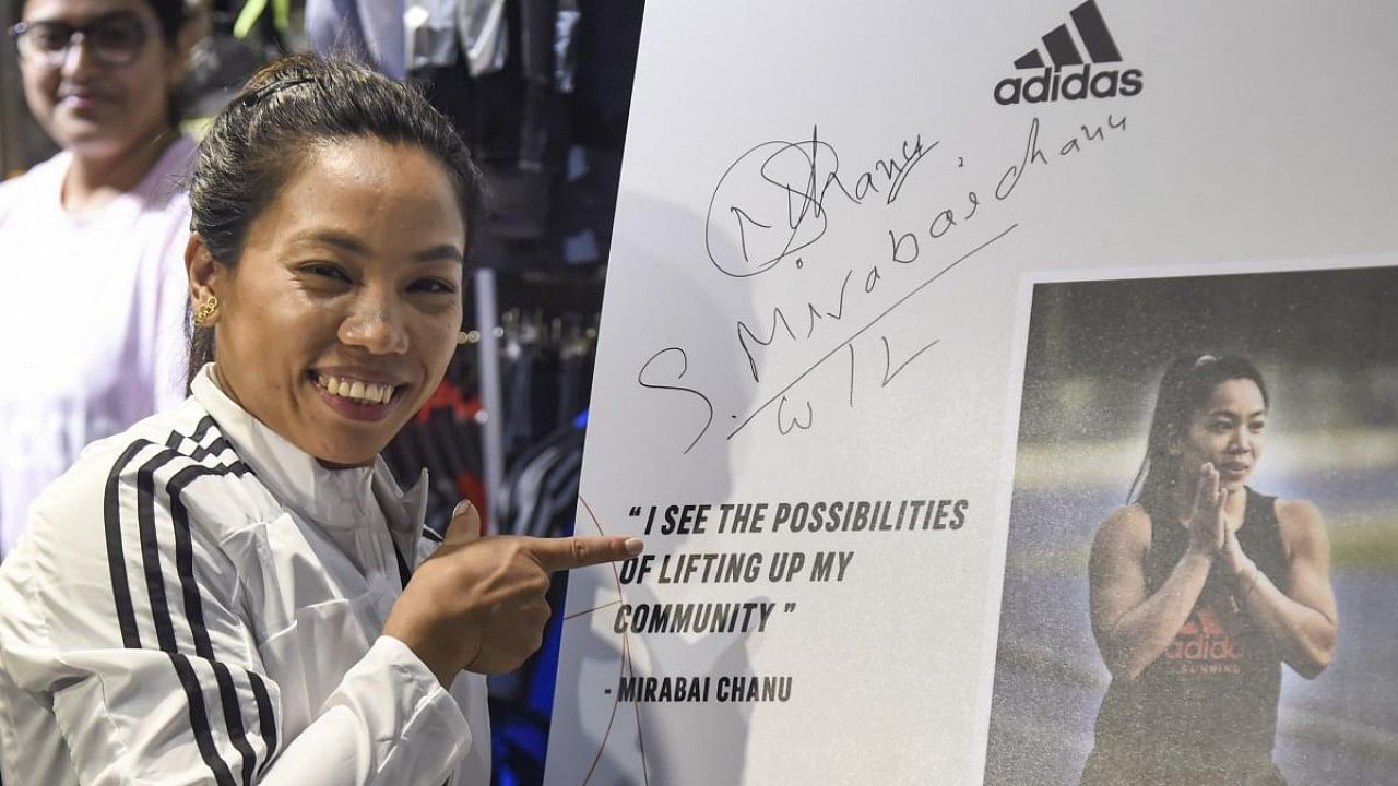 Mirabai Chanu signs autograph during her visit to an adidas store. Credit: PTI Photo