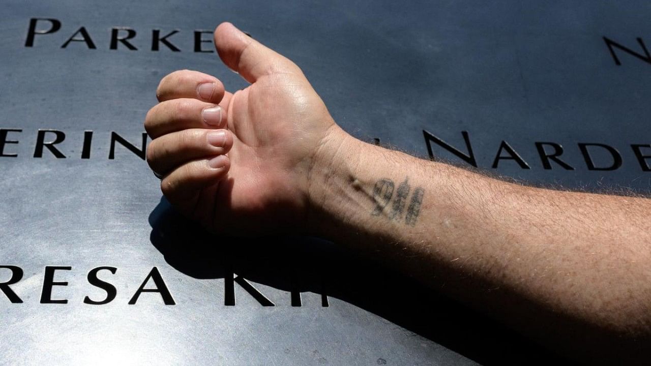 A survivor of the September 11, 2001 World trade Center attacks shows a 911 tattoo on his right wrist at the 9/11 memorial. Credit: AFP Photo