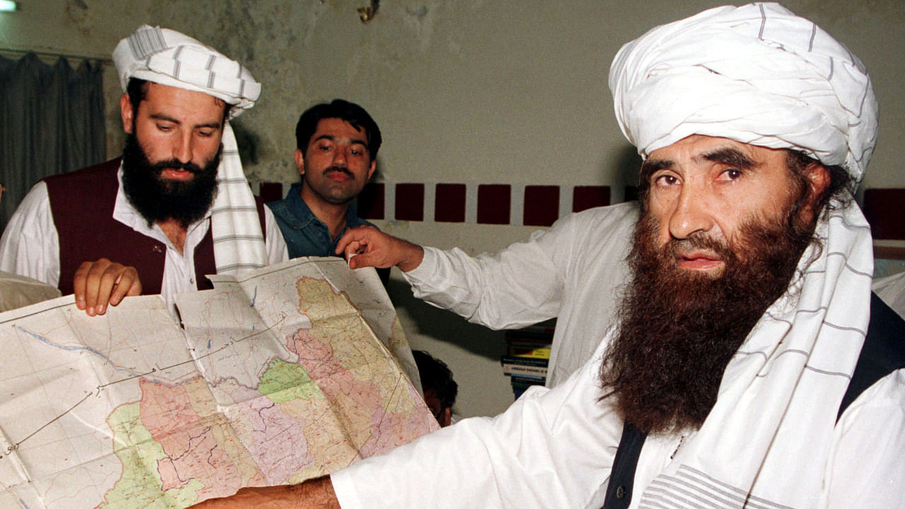 Jalaluddin Haqqani (R), the Taliban's Minister for Tribal Affairs, points to a map of Afghanistan during a visit to Islamabad, Pakistan, October 19, 2001, as his son Naziruddin (L) looks on. Credit: Reuters File Photo