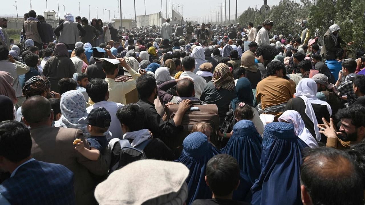 Afghans gather on a roadside near the military part of the airport in Kabul on August 20, 2021, hoping to flee from the country after the Taliban's military takeover of Afghanistan. Credit: AFP photo