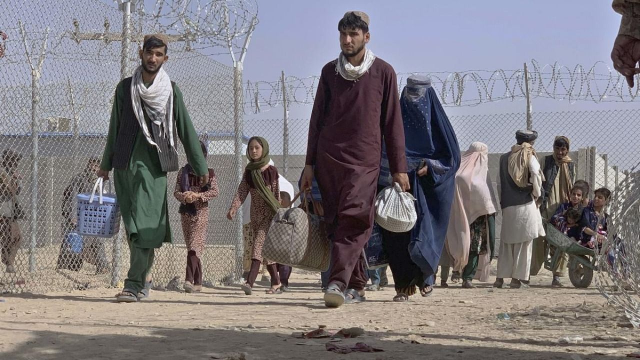 Afghans walk through a security barrier as they enter Pakistan through a border crossing point in Chaman, Pakistan, Thursday, Aug. 26, 2021. Hundreds of Pakistanis and Afghans cross the border daily through Chaman to visit relatives, receive medical treatment and for business-related activities. Pakistani has not placed any curbs on their movement despite recent evacuations from Kabul. Credit: AP/PTI Photo