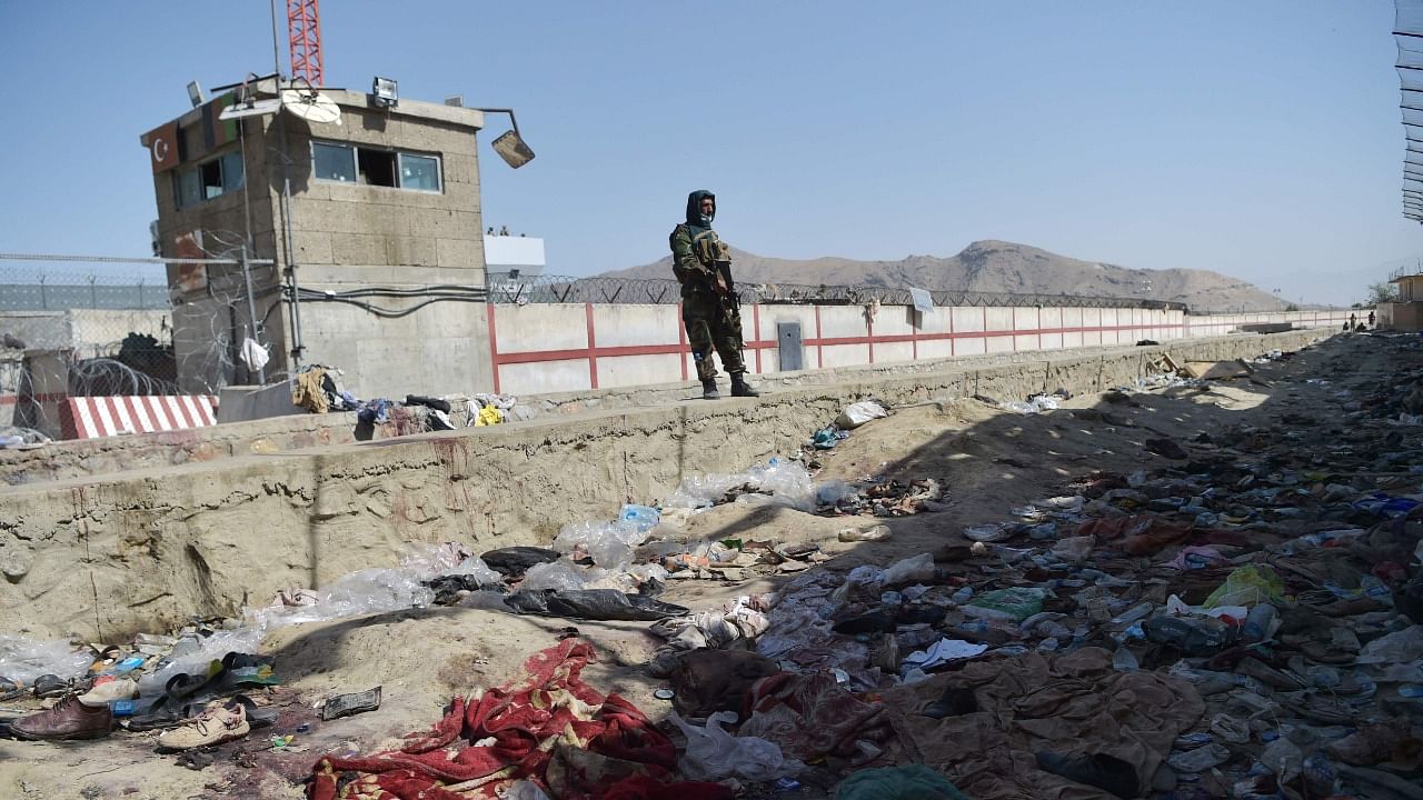 A Taliban fighter stands guard at the site of the August 26 twin suicide bombs, which killed scores of people including 13 US troops, at Kabul airport on August 27, 2021. Credit: AFP Photo