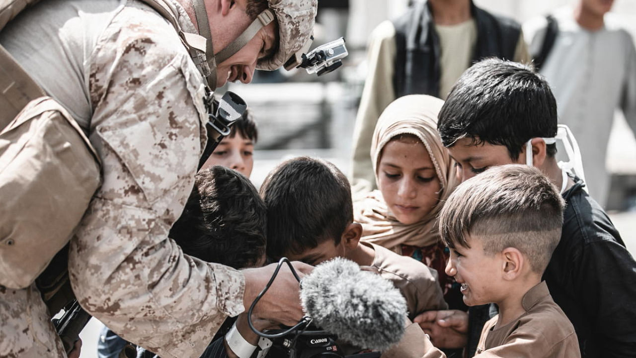 A US Marine shows his video camera to children awaiting evacuation at Hamid Karzai International Airport, Afghanistan. Credit: Reuters Photo