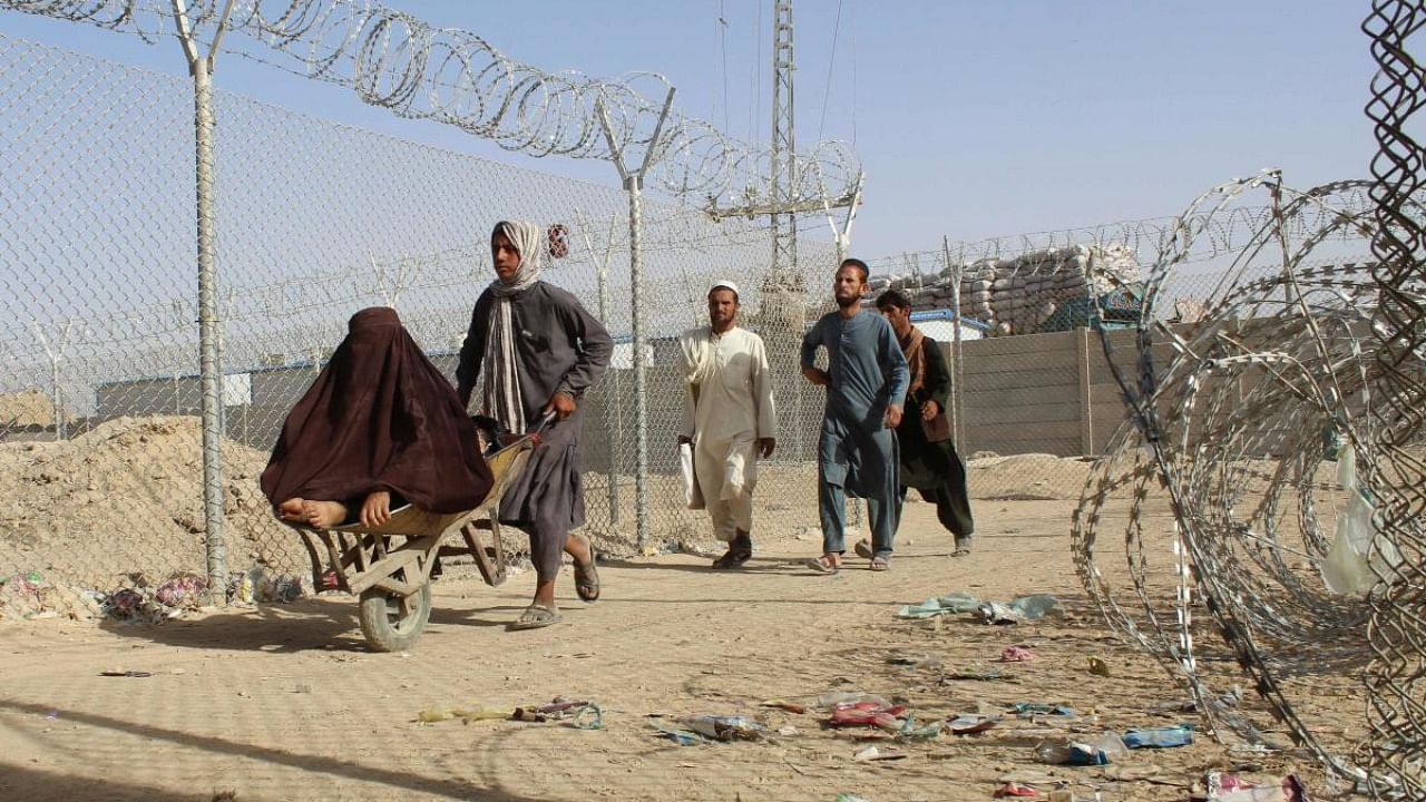 Afghans walk along a fenced corridor after crossing into Pakistan through the Pakistan-Afghanistan border crossing point in Chaman. Credit: AFP Photo
