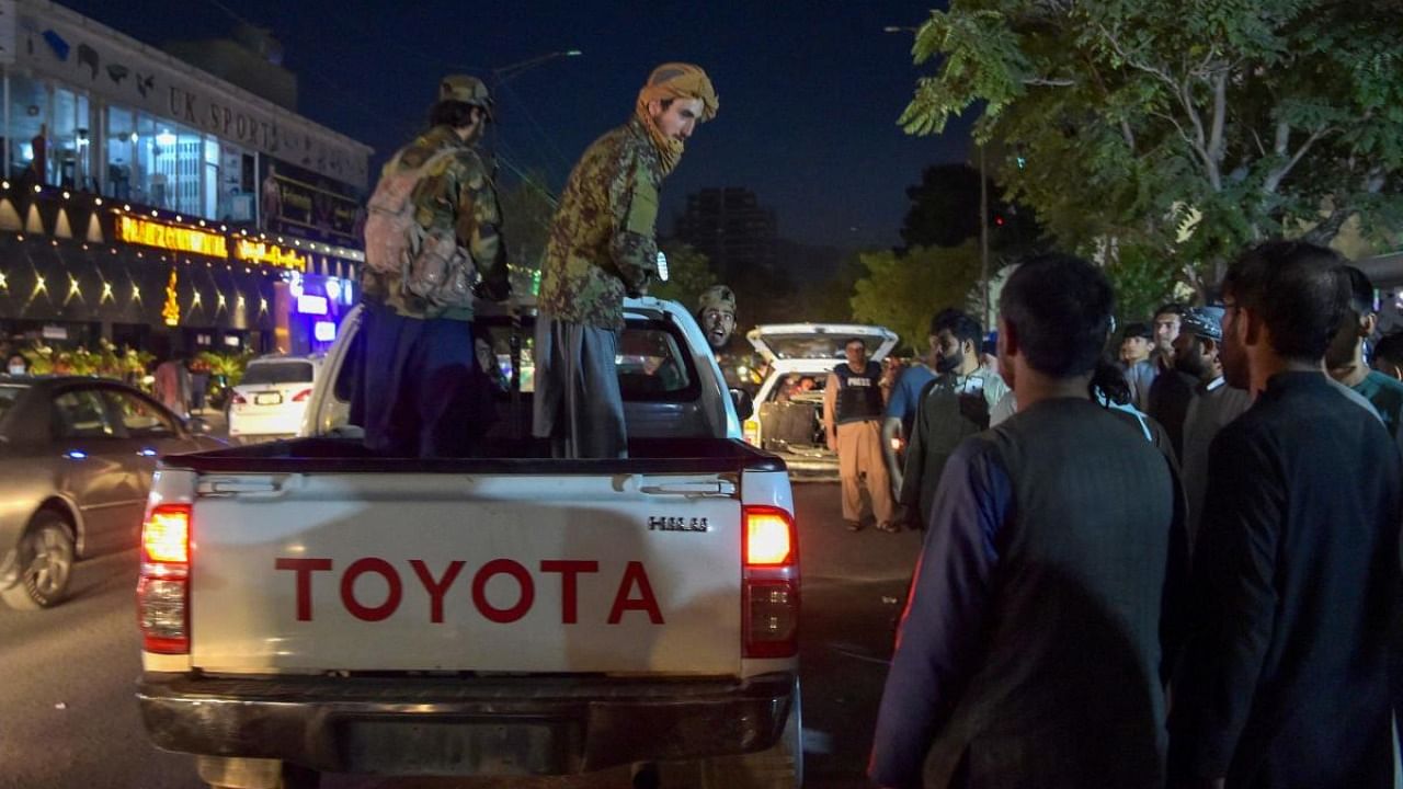 Taliban fighters stand on a pickup truck outside a hospital as volunteers bring injured people for treatment after two powerful explosions, which killed at least six people, outside the airport in Kabul. Credit: AFP Photo