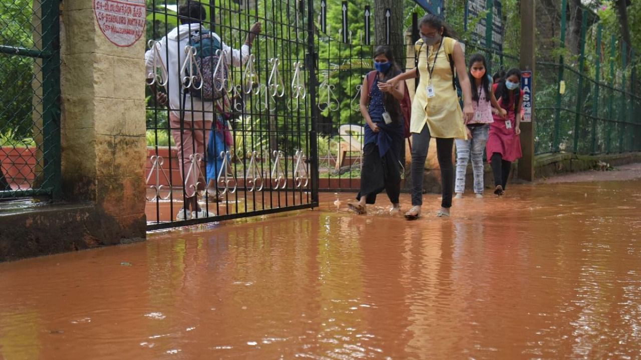 Students wade through water following heavy rains at Malleswaram in Bengaluru on Friday. Credit: DH Photo/Pushkar V