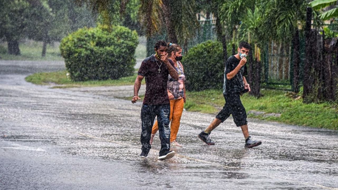 People walk under the rain in Havana on August 27, 2021, as Hurricane Ida passes through eastern Cuba. Credit: AFP Photo