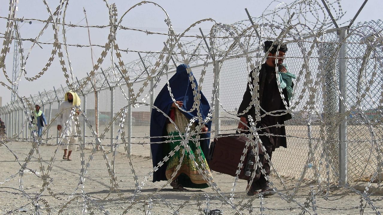Afghan nationals walk along a fenced corridor after crossing into Pakistan through the Pakistan-Afghanistan border crossing point in Chaman on August 28, 2021 following the Taliban's military takeover of Afghanistan. Credit: AFP Photo