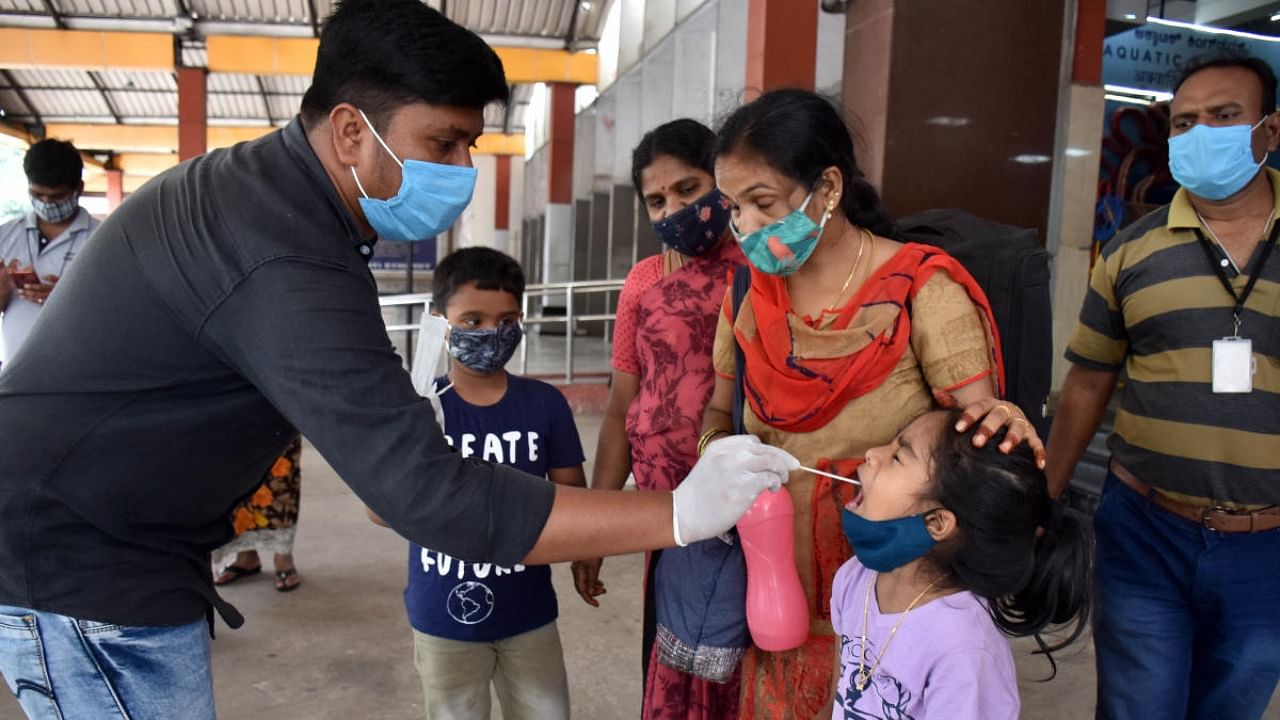 A healthcare personnel takes the sample of a girl for Covid-19 at KSR Railway Station in Bengaluru. Credit: DH photo