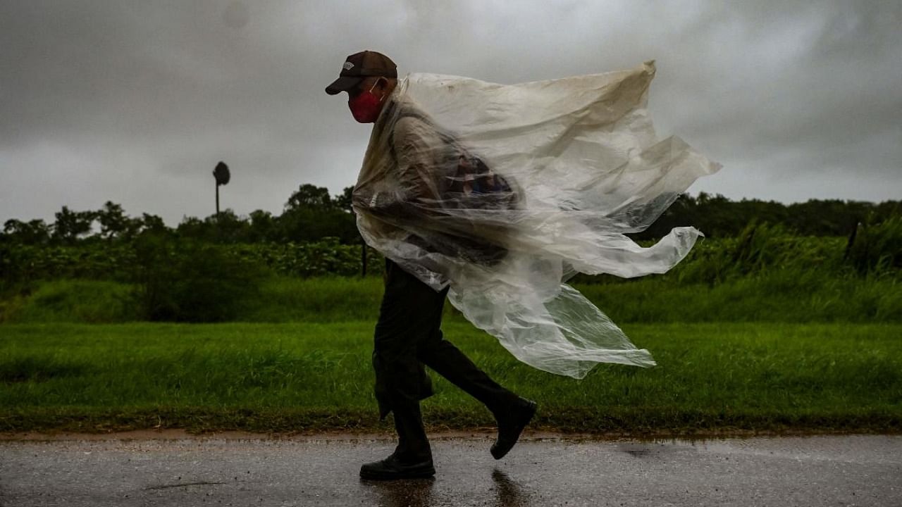 A man walks under the rain in Batabano, Mayabeque province, about 60 km south of Havana, on August 27, 2021, as Hurricane Ida passes through eastern Cuba. Credit: AFP Photo