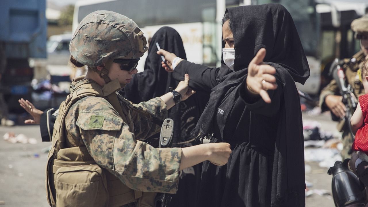 A US Marine checks a woman as she goes through the Evacuation Control Center (ECC) during an evacuation at Hamid Karzai International Airport, Kabul. Credit: Reuters photo/US Marine Corps/Staff Sgt. Victor Mancilla/Handout