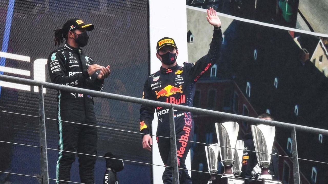First-placed Red Bull's Dutch driver Max Verstappen (R) waves as he arrives on the podium next to third-placed Mercedes' British driver Lewis Hamilton after the Formula One Belgian Grand Prix at the Spa-Francorchamps circuit. Credit: AFP Photo
