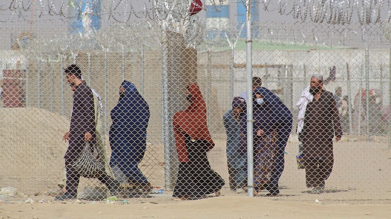Afghan nationals walk along a fenced corridor as they enter Pakistan through the Pakistan-Afghanistan border crossing point in Chaman on August 30, 2021, as dreading another period of harsh rule after the Taliban's rapid takeover following the US troop withdrawal, thousands have been desperately trying to flee Afghanistan. Credit: AFP Photo