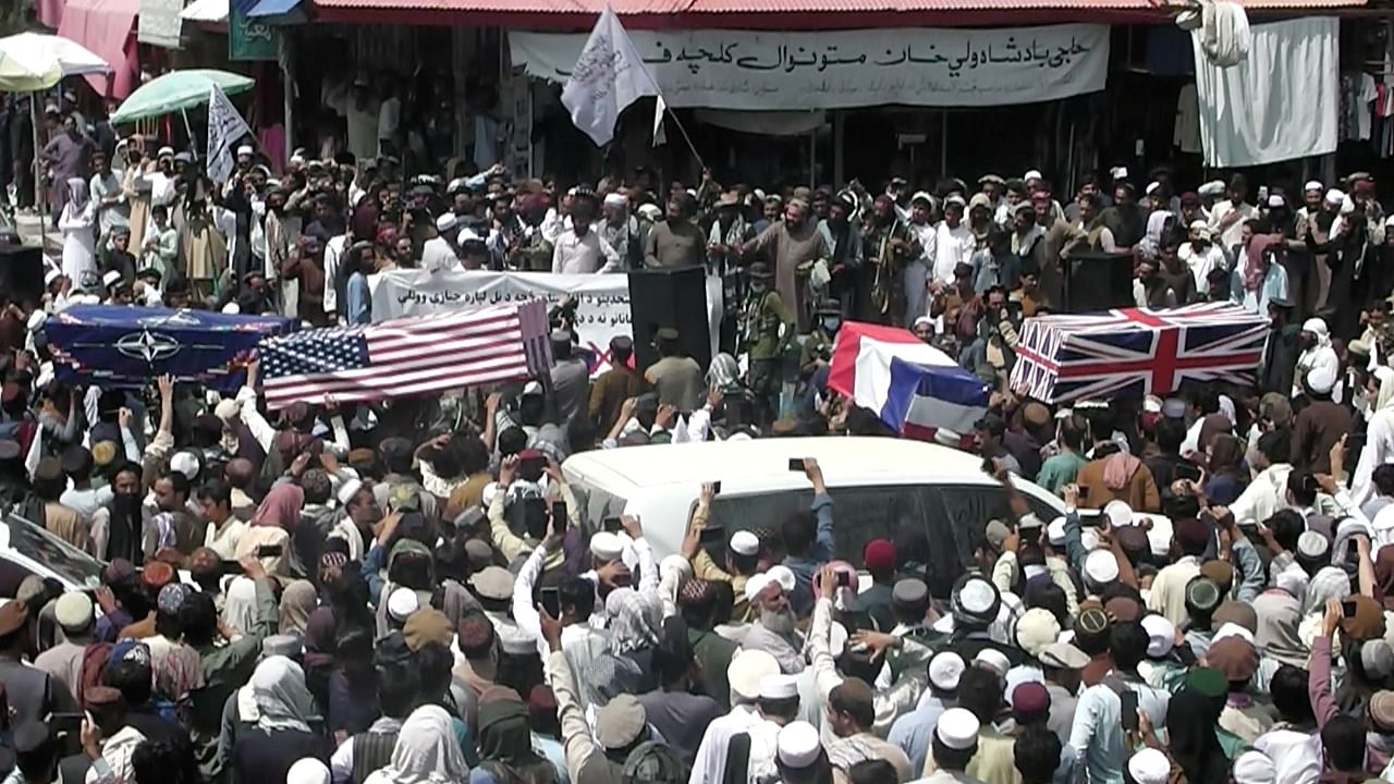 Crowd carries makeshift coffins draped in NATO's, US and a Union Jack flags during a pretend funeral on a street in Khost, Afghanistan August 31, 2021, in this screen grab obtained from a social media video. Credit: ZHMAN TV/via Reuters