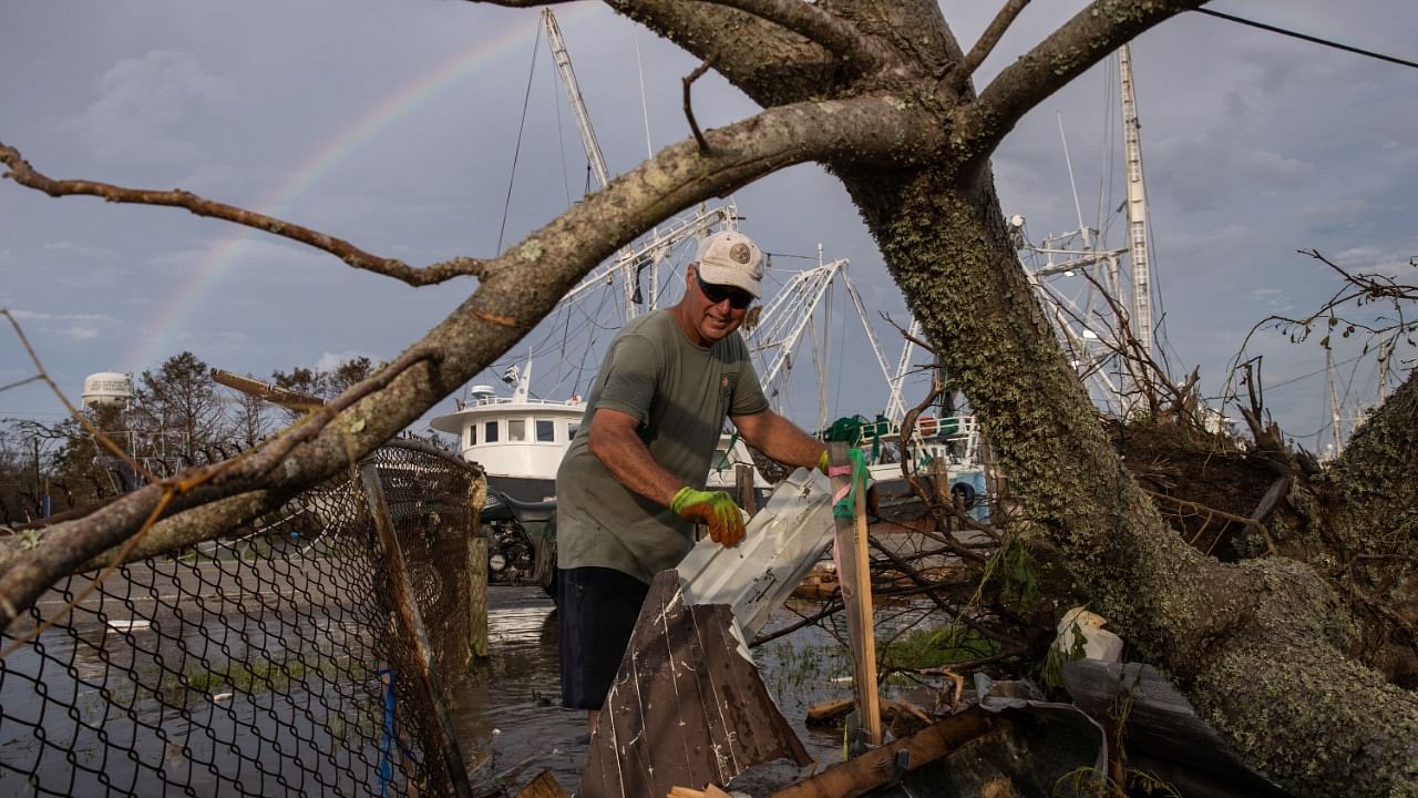 A rainbow is seen in the background as Jody Galliano, who said he is related to the founders of the town, clears debris from his yard in the aftermath of Hurricane Ida in Galliano, Louisiana. Credit: Reuters Photo