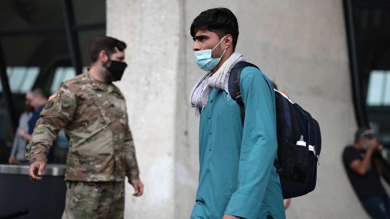 A refugee walks to board a bus at Dulles International Airport that will take them to a refugee processing center after being evacuated from Kabul following the Taliban takeover of Afghanistan on August 31, 2021 in Dulles, Virginia. Credit: AFP Photo