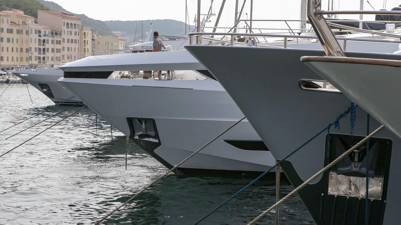 In this file photo taken on August 11, 2021 employees work on luxury yachts in the port of Bonifacio in the south of the French Mediterranean island of Corsica. Credit: AFP Photo